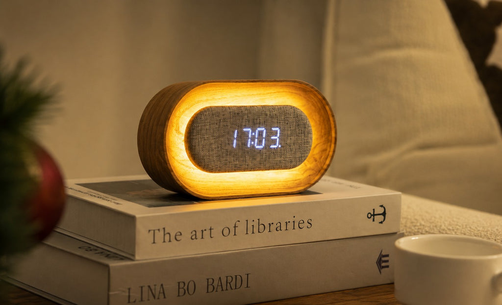 Gingko Design – Reloj Lumos - Ovalado Fresno Blanco, despertador de madera y tela, colocado sobre unos libros, luz cálida