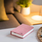 Gingko Design – Lampe Smart Book LED - Lin Rose Poudré - 2 Tailles, livre rose posé sur une table basse dans un salon