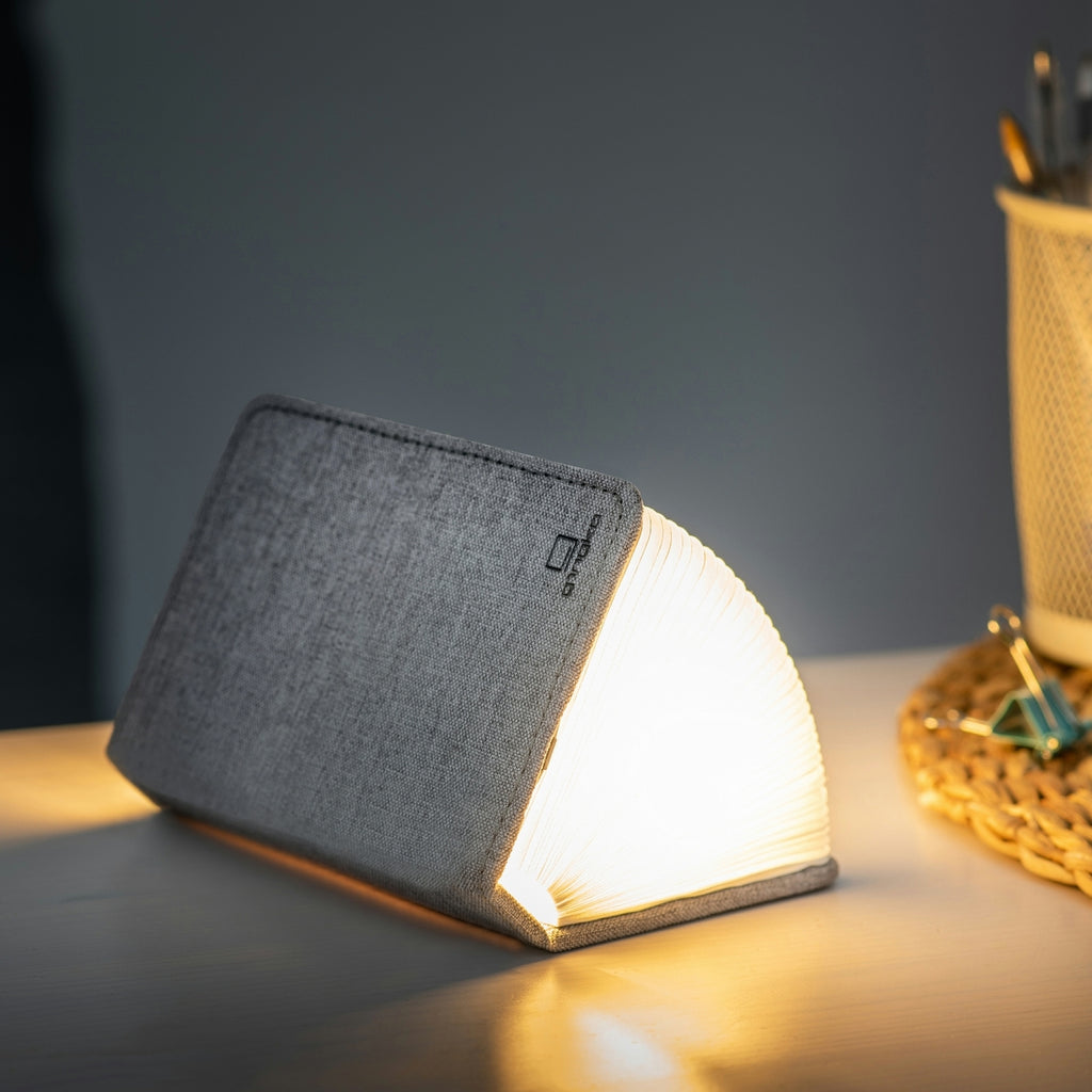 Gingko Design – Lámpara Smart Book LED - Lino Gris Urbano - 2 Tamaños, lámpara libro abierta en un escritorio, luz cálida, ambiente acogedor