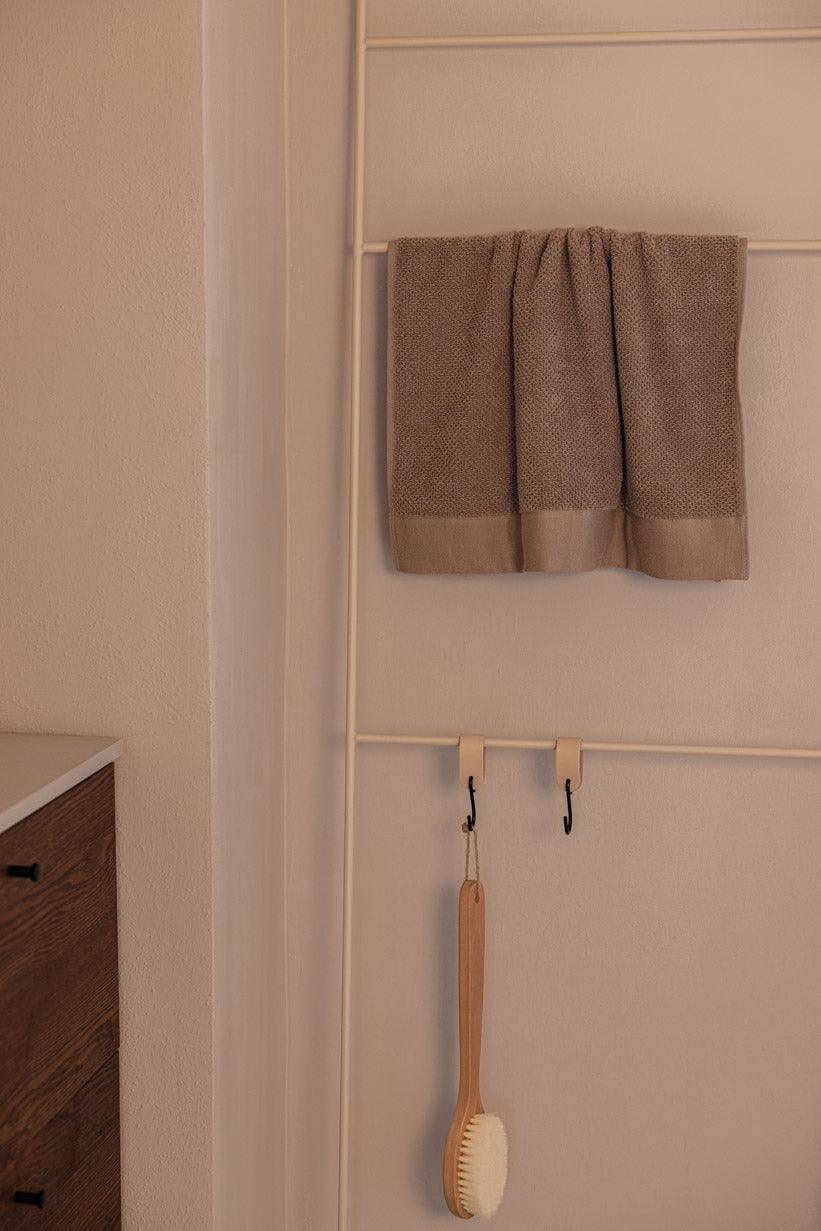 Handtuchleiter mit einem handtuch und einer Bürste, ideal für Badezimmeraccessories.