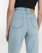Jean droit en denim bleu clair 100 % coton avec taille haute et coupe large, s'adaptant parfaitement à toutes les morphologies féminines.