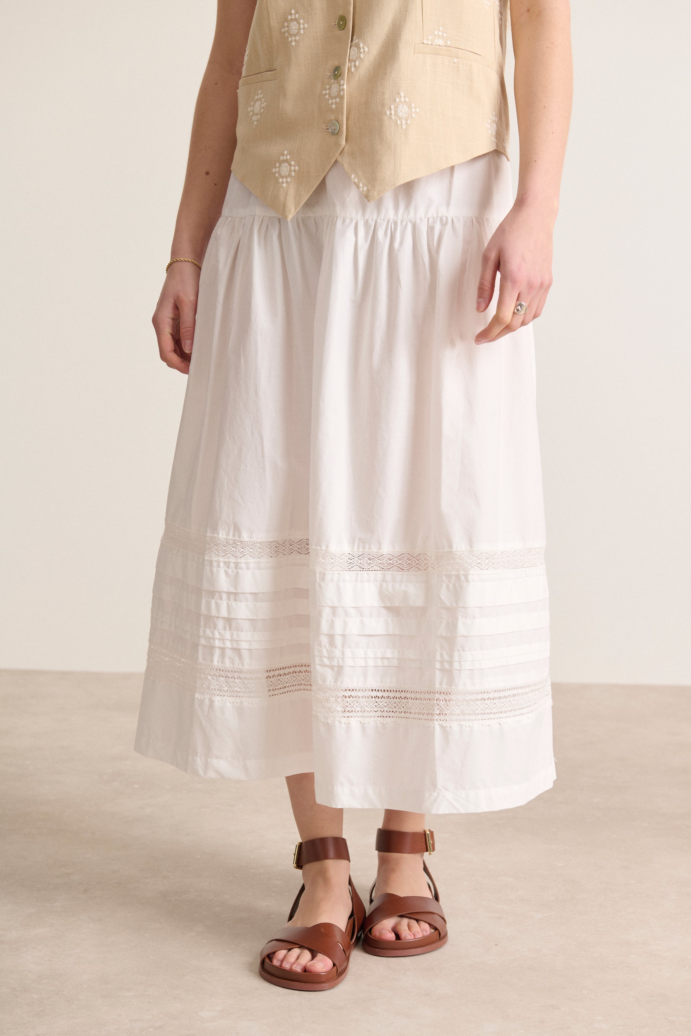 Jupe fluide en popeline doublée, taille élastique, ornée de découpes et de plis, avec dentelle raffinée