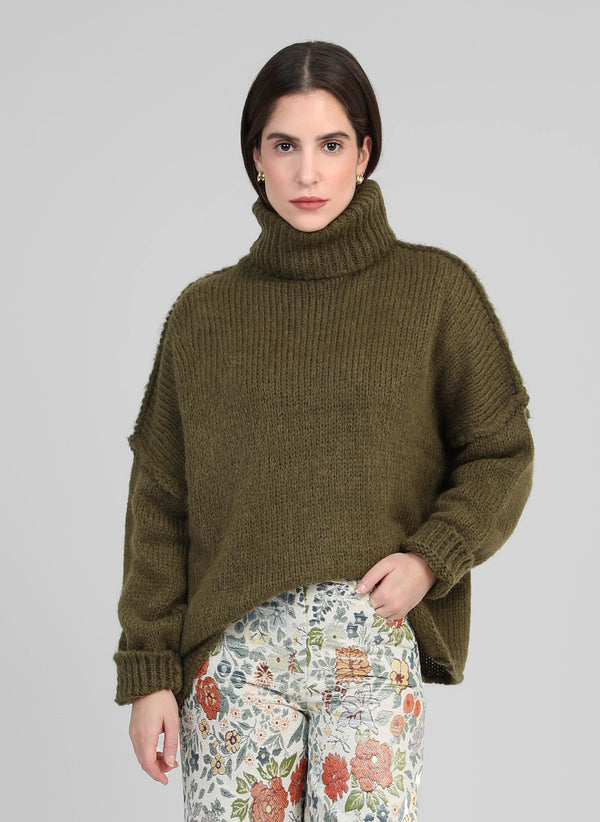 An'ge – Maglione Lejoko Army, modella che indossa un maglione verde oliva a collo alto e pantaloni a fiori