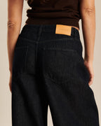 Jean large en denim brut foncé avec une coupe ample et confortable, fabriqué en coton, idéal pour les femmes recherchant un style à la fois décontracté et élégant.