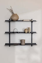 Wandregal LINARA aus Metall mit minimalistischem Design und vier Ablagen, dekoriert mit Vasen und Büchern.