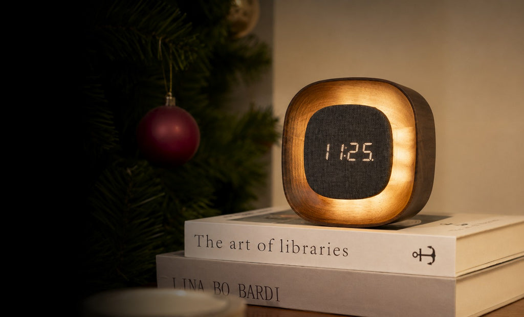 Gingko Design – Orologio Lumos - Quadrata Noce, sveglia in legno e tessuto, posata su dei libri, vicino a un albero di Natale