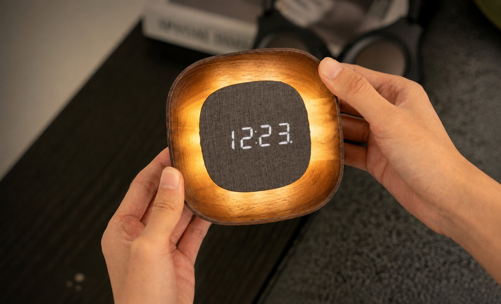 Gingko Design – Orologio Lumos - Quadrata Noce, una persona tiene in mano un orologio in legno con display digitale