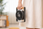 Gingko Design – Ventilatore Portatile Lyra - Grigio Siderale, una persona con abito chiaro tiene un ventilatore portatile grigio e legno