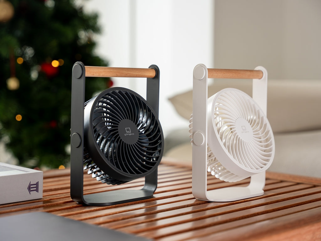 Gingko Design – Ventilatore Portatile Lyra - Grigio Siderale, due ventilatori da tavolo, uno nero e uno bianco, appoggiati su un tavolo in legno