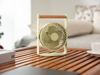 Gingko Design – Ventilatore Portatile Lyra - Grigio Siderale, ventilatore da tavolo verde chiaro con manico in legno su un tavolino basso