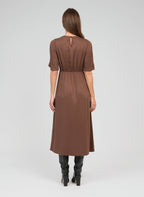 An'ge – Robe Longue Maelsa Marron, mannequin de dos portant une robe longue marron avec des bottes noires
