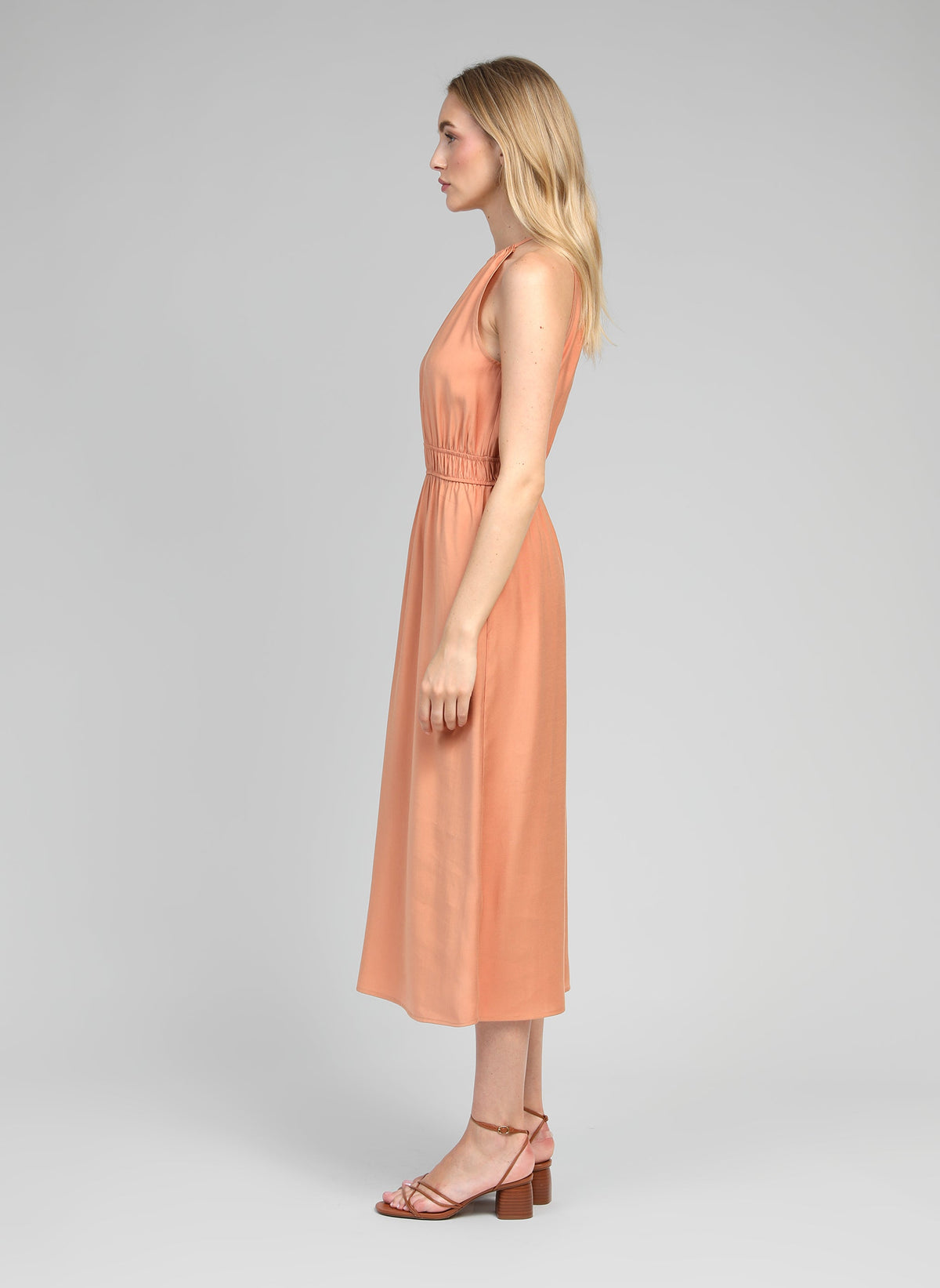 An'ge – Mendaly Terracotta lang kjole, model iført en ferskenfarvet midikjole, set i profil