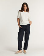 Pantalon en popeline bleu marine pour femme, coupe droite et ample, matière légère en coton idéale pour l'été, avec poches latérales et chevilles retroussées.