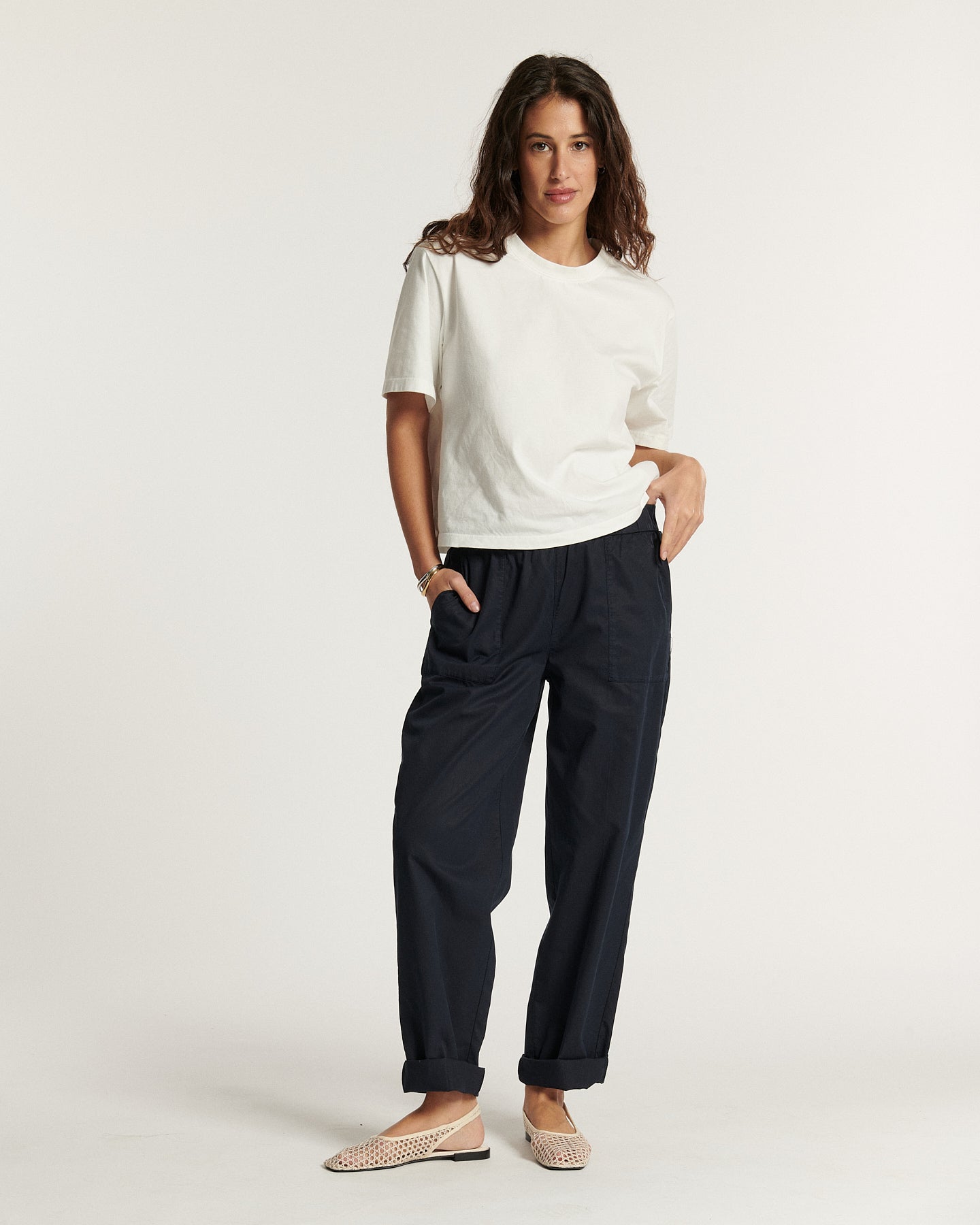 Pantalon en popeline bleu marine pour femme, coupe droite et ample, matière légère en coton idéale pour l'été, avec poches latérales et chevilles retroussées.