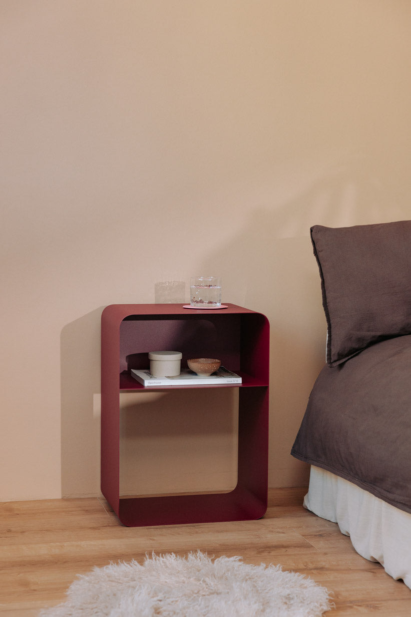 Stehender Nachttisch en forma minimalista con pulverbeschichteter Oberfläche und sanften Rundungen.