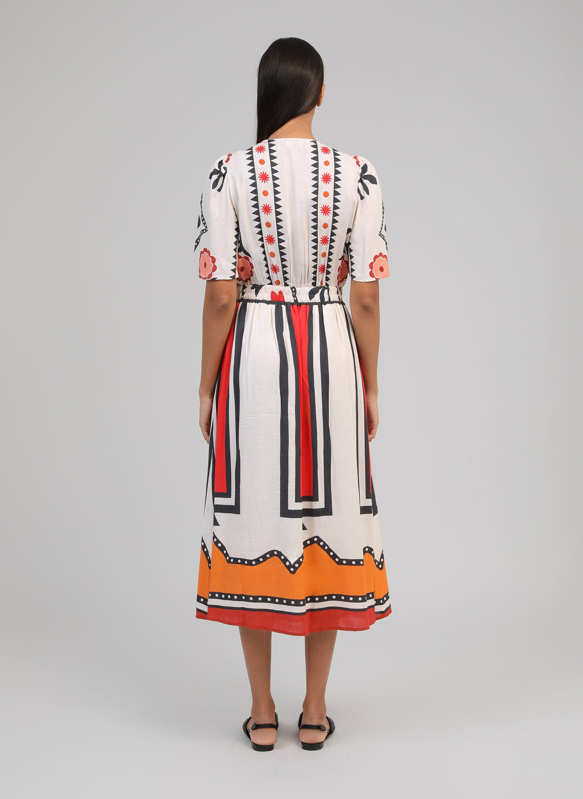 An'ge – Vestido Midi Odemaria Sage Ecru, vestido midi de motivos coloridos llevado de espaldas por una modelo
