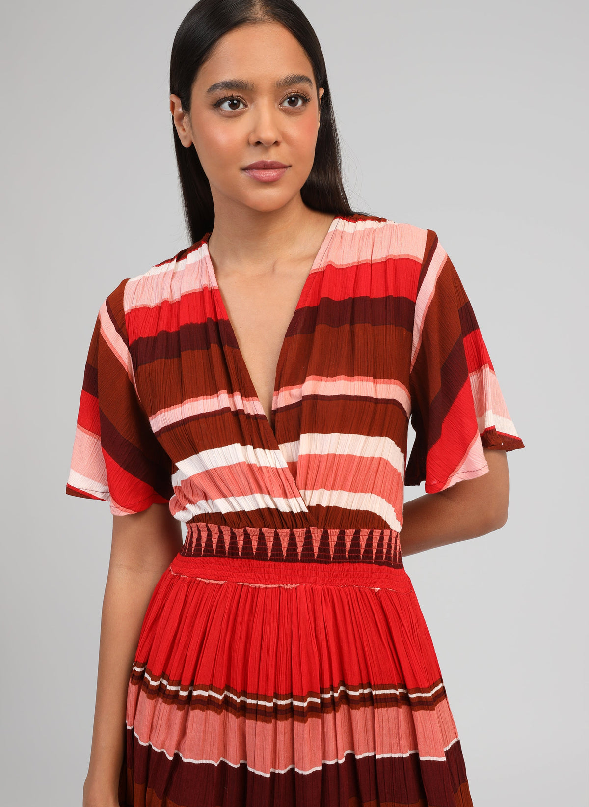 An'ge – Robe Courte Oflyma Sulana Bordeaux, model iført en lang plisseret kjole med flerfarvede striber, set forfra