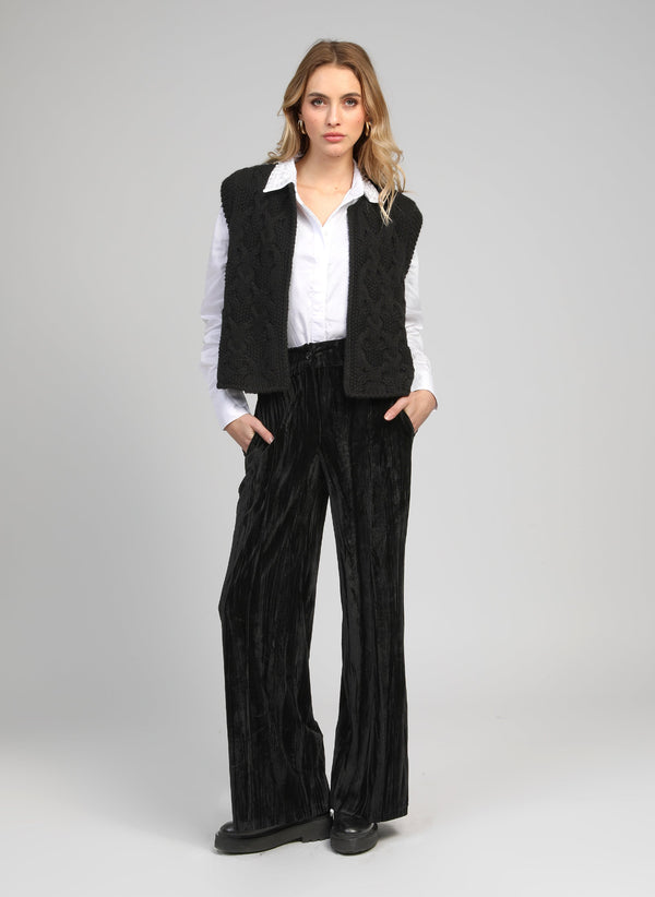 An'ge – Patrilou Trousers in Black, model wearing a black quilted gilet and black pleated trousers