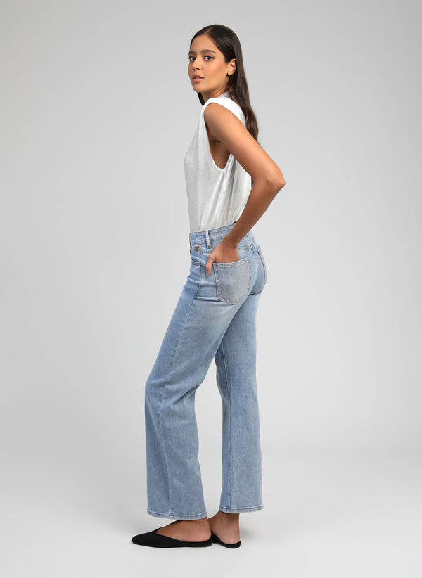 An'ge – Pipoche Bleu Ciel Trousers, model in profile wearing a white vest top and light blue jeans