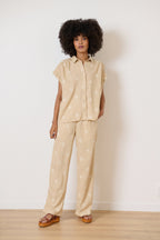 Beige cotton shirt with shirt collar and sleeves covering the shoulder with cut-out details and gathers on the shoulder and back 