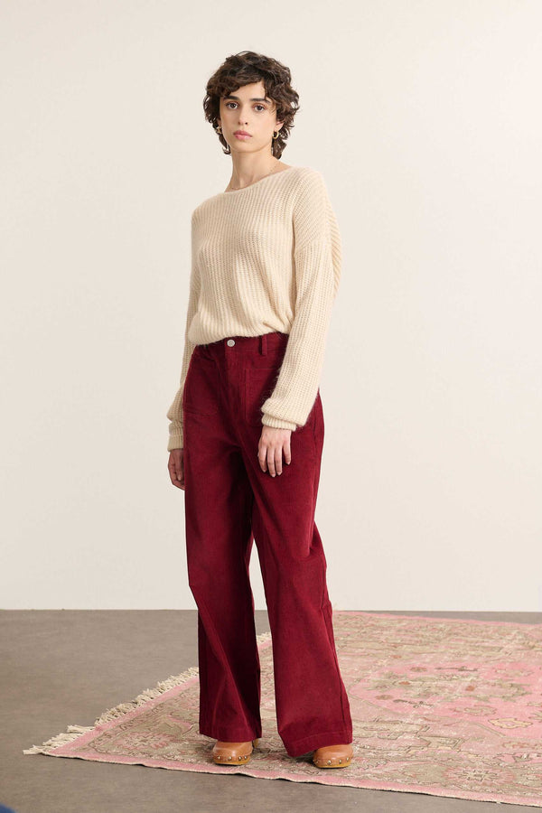 Mannequin femme de face portant un pull beige à manches longues, coupe droite avec col rond devant et décolleté au dos.