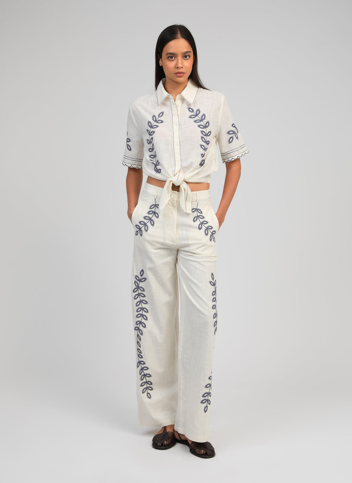 An'ge – Rossalie Trousers Ecru, model wearing a white co-ord set embroidered with blue botanical motifs, front view