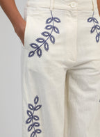 An'ge – Rossalie Trousers Ecru, off-white trousers embroidered with blue botanical motifs, worn by a model