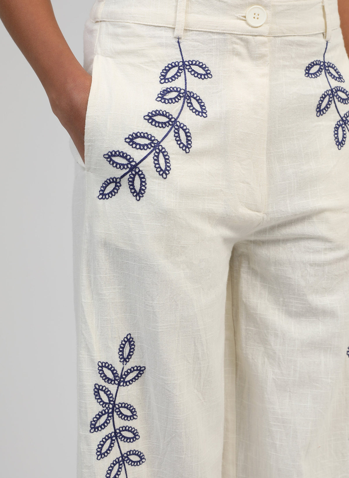 An'ge – Rossalie Trousers Ecru, off-white trousers embroidered with blue botanical motifs, worn by a model