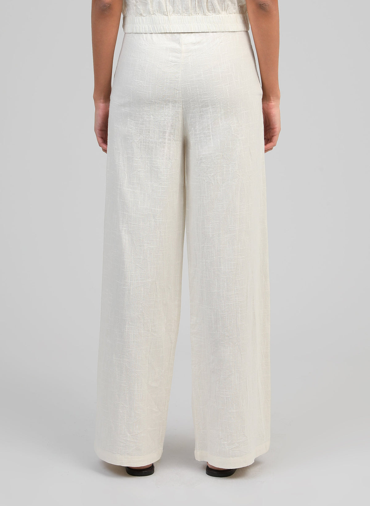 An'ge – Rossalie Trousers Ecru, off-white wide-leg linen trousers worn from behind by a model
