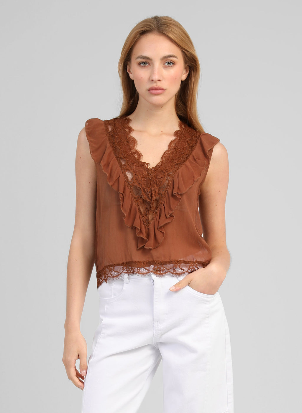 An'ge – Mouwloze top Savilma Bruin, model draagt een bruine kanten top en een witte broek