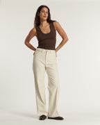 Jean femme en coton beige clair à fines rayures verticales, coupe large et droite, offrant une silhouette fluide et confortable idéale pour l'été.