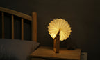 Gingko Design – Lámpara Smart Origami - Bambú Natural, lámpara de noche plegable de madera y papel, encendida, sobre una mesita de noche