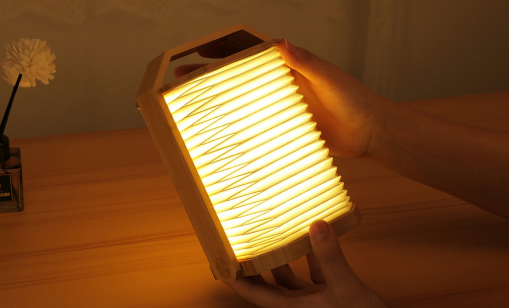 Gingko Design – Lámpara Smart Origami - Bambú Natural, lámpara plegable de madera y papel, sostenida por unas manos