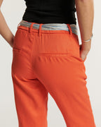 Pantalon femme en tissu Tencel orange tangerine, coupe droite avec une taille haute ajustée, ceinture rayée légère, idéal pour un look estival élégant.
