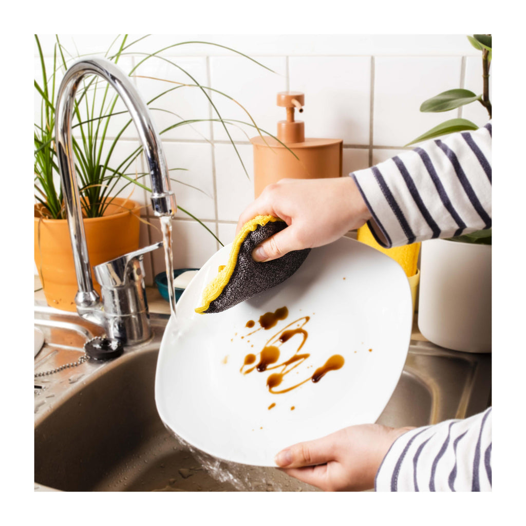 Eponge lavable jaune nettoyant une assiette
