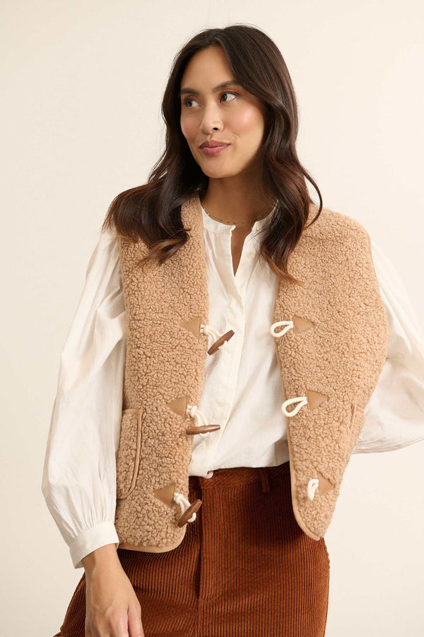 Confeccionado completamente en poliéster, chaleco POLETTE en color beige con cierre trenzado de alamar.