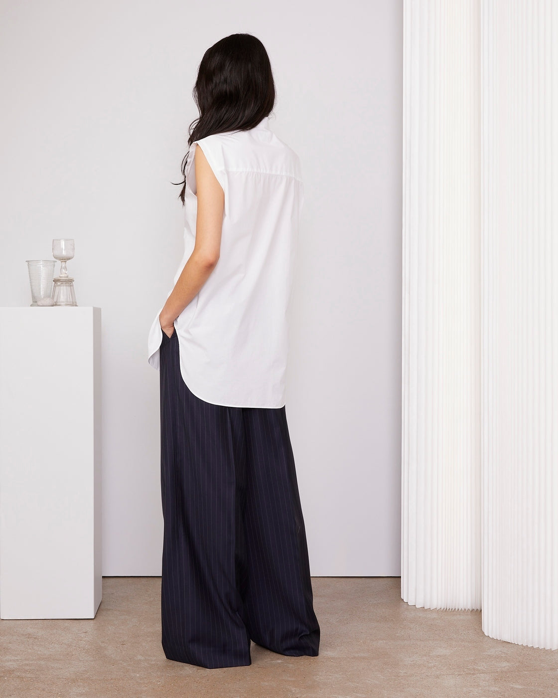 Officine Générale – Chemise Amelia - Blanc - Femme, mannequin de dos portant une chemise blanche sans manches et un pantalon large bleu marine