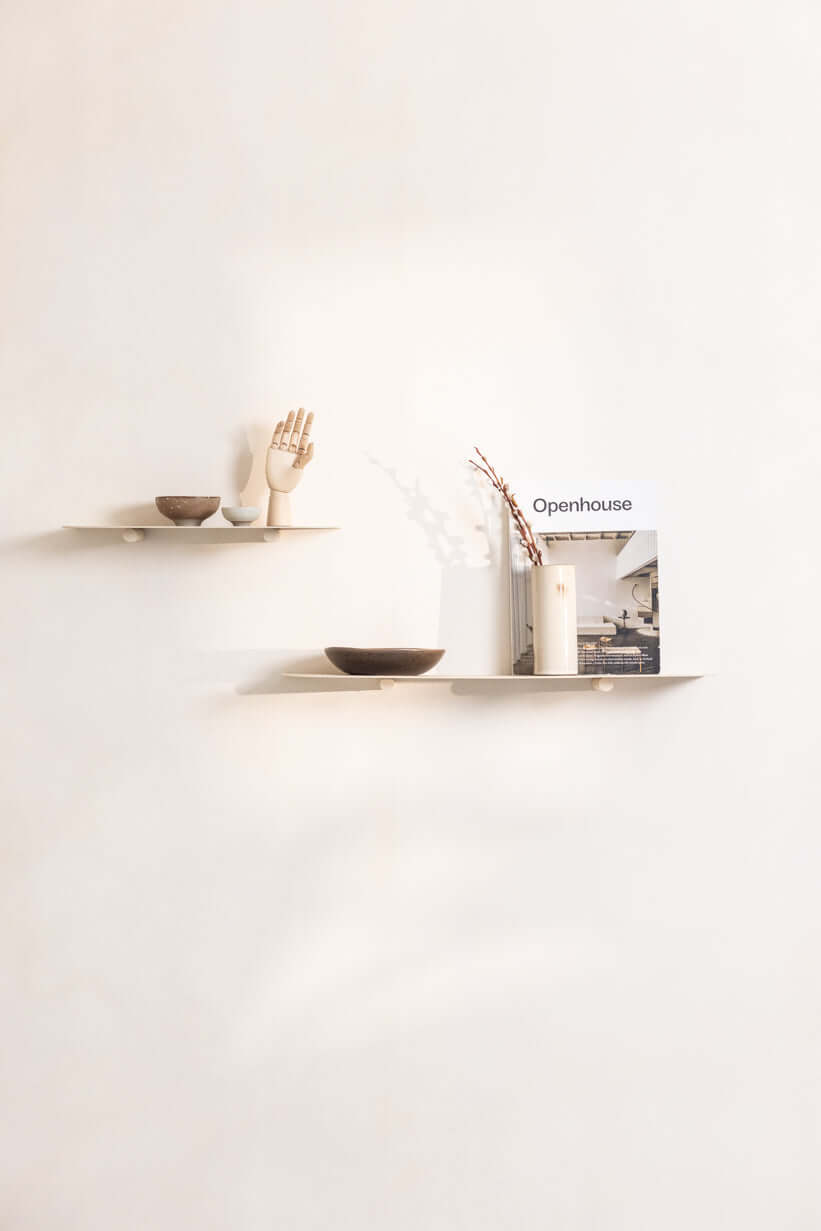 Modern Wandregal LENN aus Metall mit dekorativen Objekten und einem Magazin an der Wand.