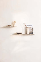 Modern Wandregal LENN aus Metall mit dekorativen Objekten und einem Magazin an der Wand.