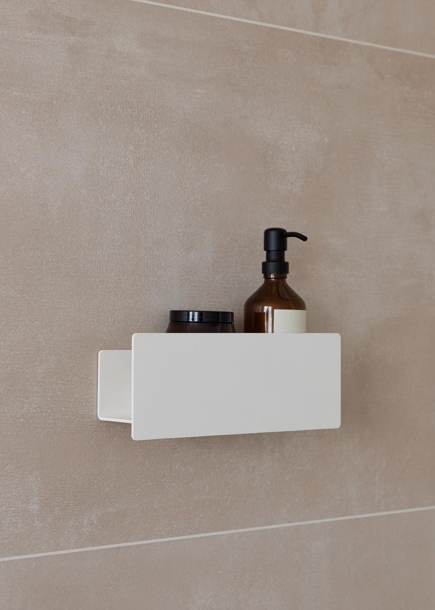 Duschable SHEA an einer Wand mit Pflegeprodukten in der Dusche, schlichtes Design für optimal Aufbewahrung.