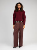 An'ge – Pantaloni Pepina Chocolat, modella che indossa un maglione bordeaux e pantaloni marroni con cintura