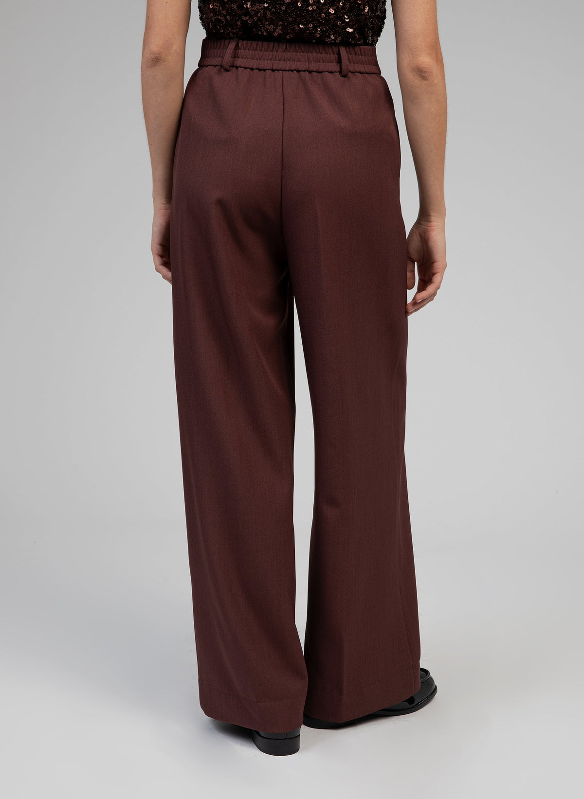 An'ge – Hose Perlina Schokolade, dunkelbraune Hose, von hinten an einem Model getragen, elastischer Bund
