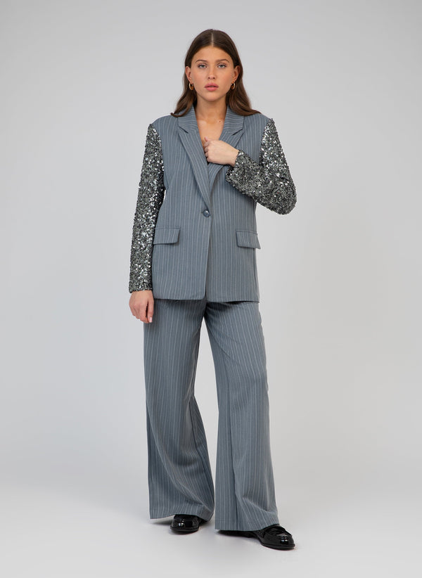 An'ge – Philiona Trousers Blue, model wearing a grey striped blazer and trousers set, sequinned sleeves