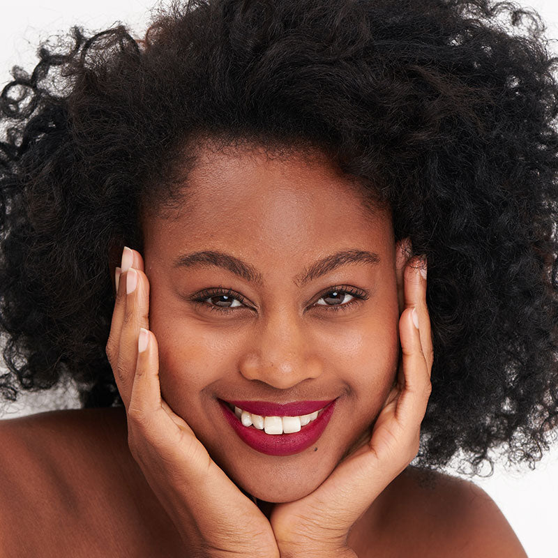 Plum shade of natural and clean Pomponne lipstick on dark skin